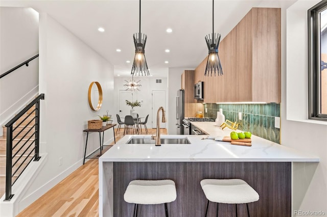 1713 Grove St, Denver, CO 80204 - kitchen featuring a sink, modern cabinets, high quality appliances, light wood-style floors, and a kitchen bar