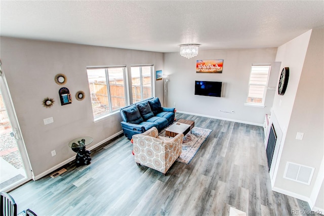 15920 Hayloft Ln, Parker, CO 80134 - living room with a fireplace, wood finished floors, a textured ceiling, a chandelier, and baseboards