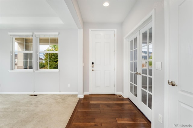 foyer entrance with french doors, dark carpet, and a healthy amount of sunlight