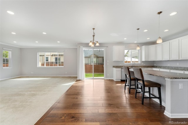 kitchen with ornamental molding, dark stone counters, a breakfast bar, decorative light fixtures, and white cabinets