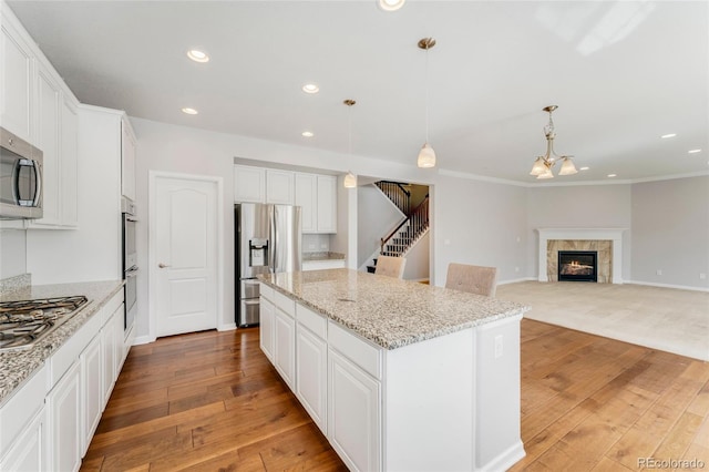 kitchen with white cabinetry, a center island, stainless steel appliances, and decorative light fixtures