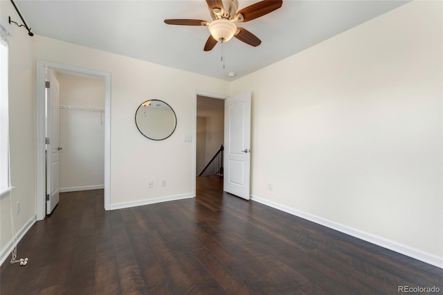 unfurnished bedroom with a closet, dark hardwood / wood-style floors, a spacious closet, and ceiling fan