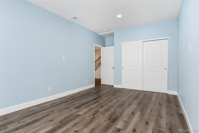 unfurnished bedroom featuring dark hardwood / wood-style flooring and a closet