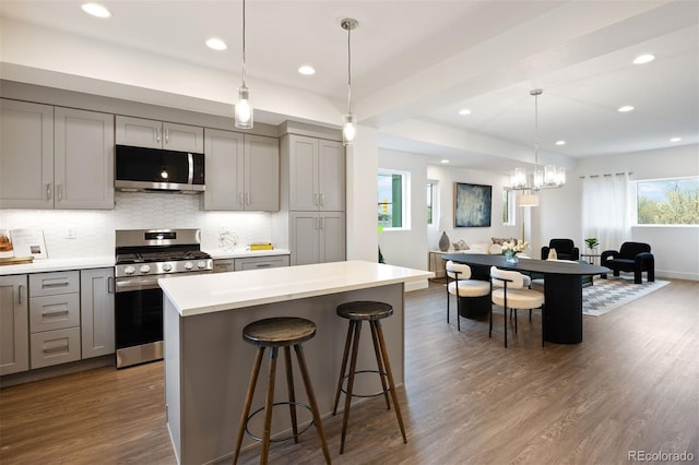 8410 W 52nd Ave, Arvada, CO 80002 - kitchen with stainless steel appliances, gray cabinets, decorative backsplash, dark wood finished floors, and a breakfast bar