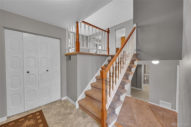 staircase with tile patterned flooring and a textured ceiling