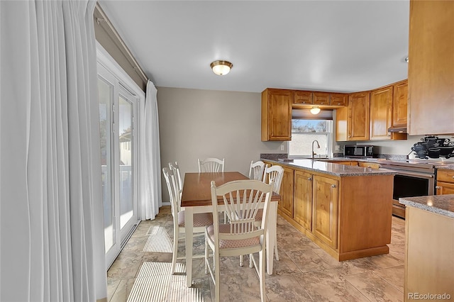 kitchen featuring stainless steel electric stove, a kitchen island, dark stone countertops, and sink