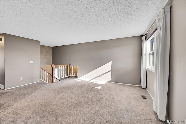 unfurnished room with light colored carpet and a textured ceiling