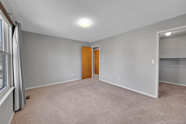 unfurnished bedroom featuring a walk in closet, light carpet, and multiple windows