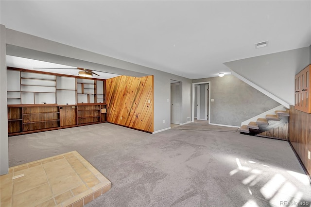 unfurnished living room with light colored carpet and wooden walls