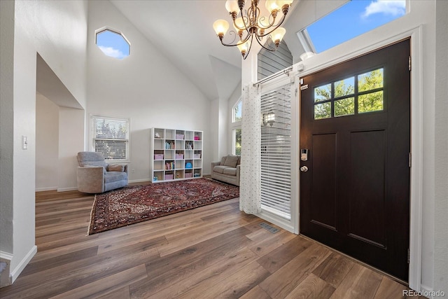 foyer featuring high vaulted ceiling, a chandelier, a wealth of natural light, and hardwood / wood-style floors