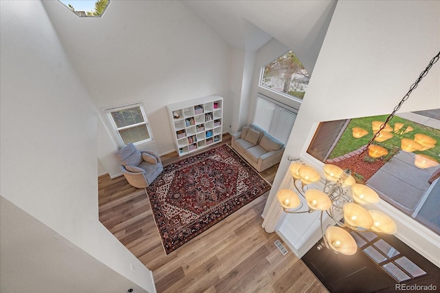 living room with a towering ceiling, a chandelier, and hardwood / wood-style flooring