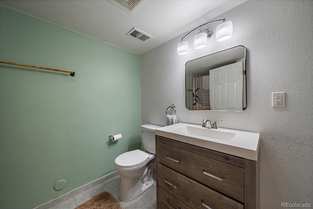 bathroom with a textured ceiling, tile patterned flooring, vanity, and toilet