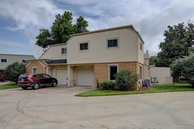 1769 S Lee St Unit B, Lakewood, CO 80232 - view of front of house with concrete driveway, brick siding, a garage, and central AC unit