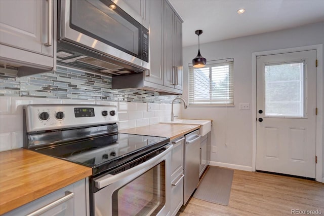 1769 S Lee St Unit B, Lakewood, CO 80232 - kitchen with stainless steel appliances, decorative backsplash, light wood-style floors, baseboards, and wood counters