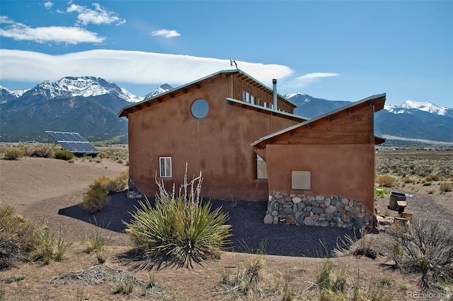 view of side of property with a mountain view and solar panels