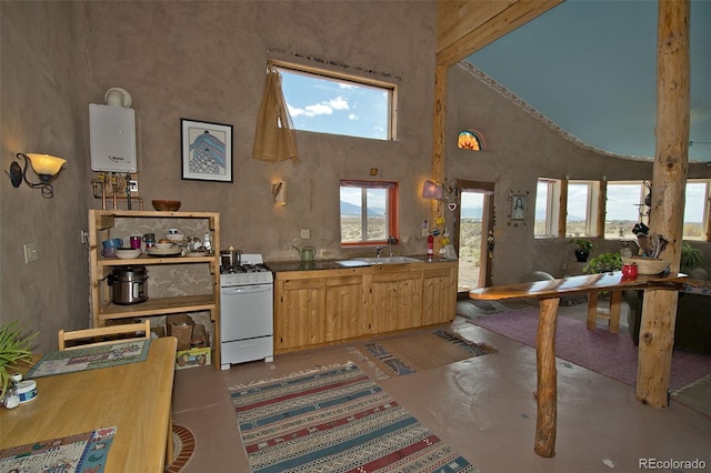 kitchen featuring light brown cabinets, high vaulted ceiling, sink, water heater, and white range with gas stovetop