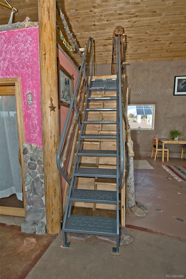 staircase with concrete flooring and wooden ceiling