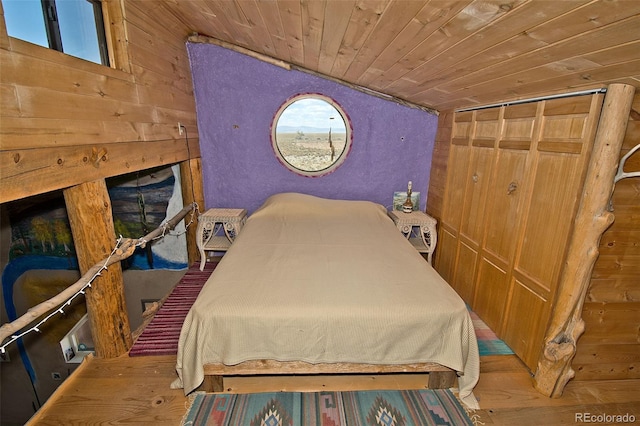 bedroom featuring lofted ceiling, wooden walls, wood-type flooring, wood ceiling, and a closet