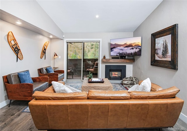 living area featuring lofted ceiling, a glass covered fireplace, baseboards, and wood finished floors