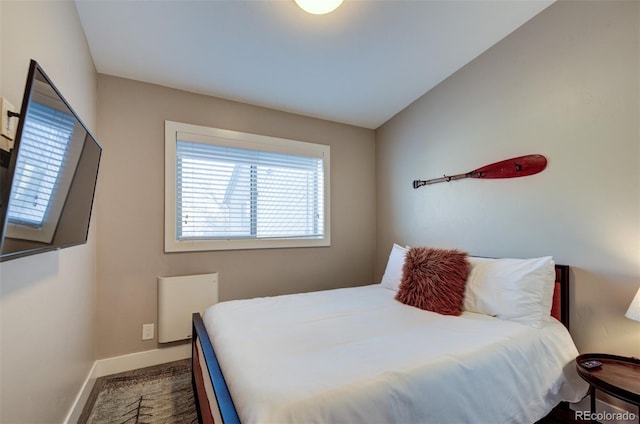 bedroom with lofted ceiling and baseboards