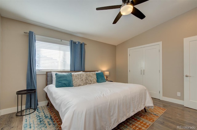 bedroom with dark wood-type flooring, lofted ceiling, and baseboards