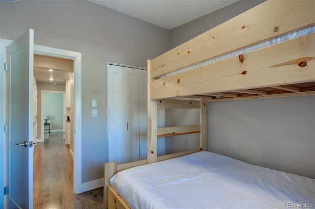 bedroom with a closet, baseboards, and wood finished floors