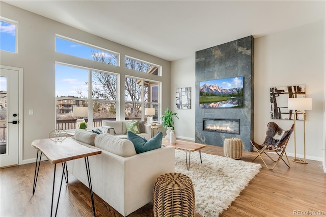 living room with a wealth of natural light, a fireplace, and wood-type flooring