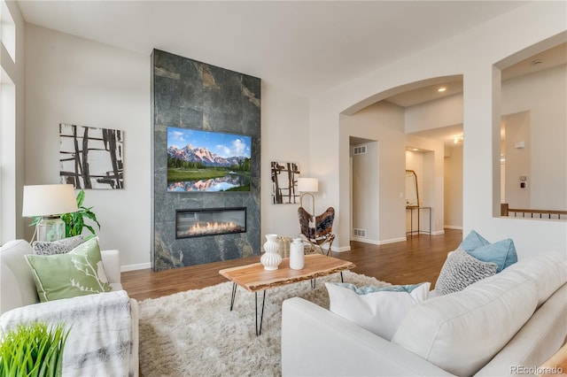 living room with dark hardwood / wood-style flooring and a tiled fireplace