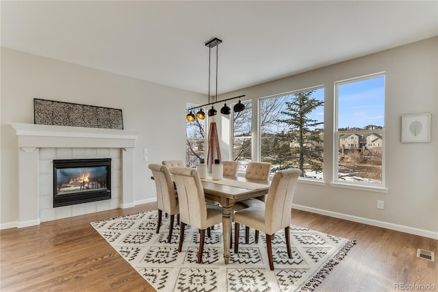 dining room with light wood-type flooring and a fireplace