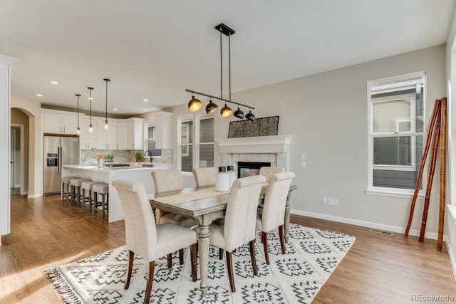 dining room featuring light wood-type flooring, a fireplace, and sink