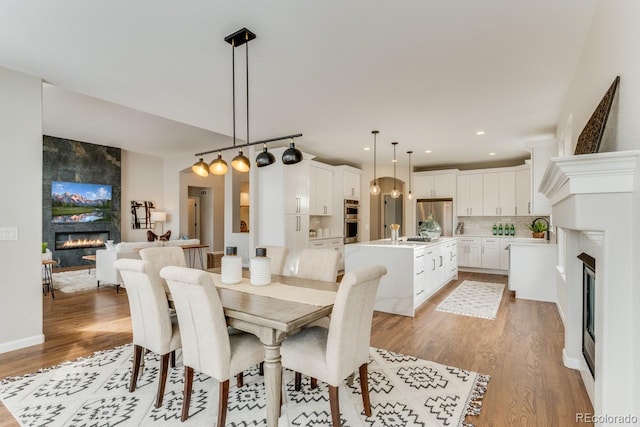 dining area with light hardwood / wood-style floors and a large fireplace