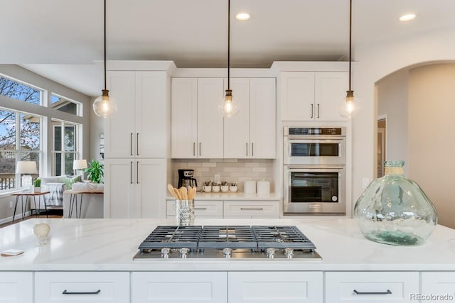 kitchen with appliances with stainless steel finishes, white cabinetry, and decorative light fixtures