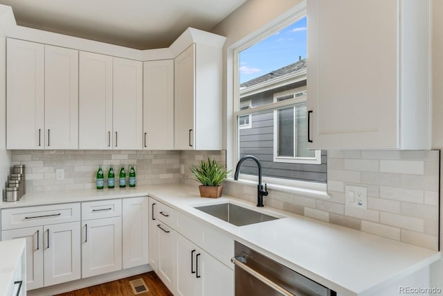 kitchen featuring decorative backsplash, sink, white cabinetry, and dishwasher