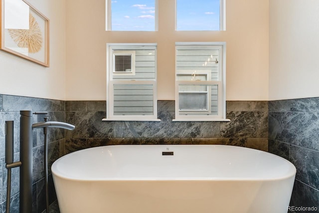 bathroom featuring a bath and tile walls