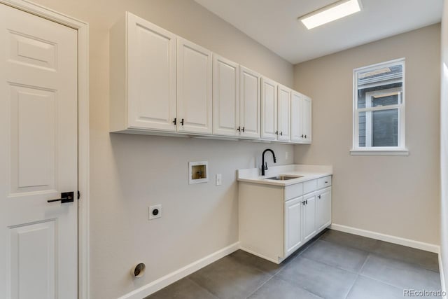 clothes washing area featuring dark tile patterned flooring, sink, washer hookup, electric dryer hookup, and cabinets