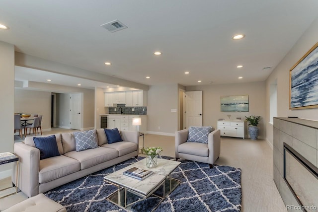 carpeted living room with wine cooler and sink