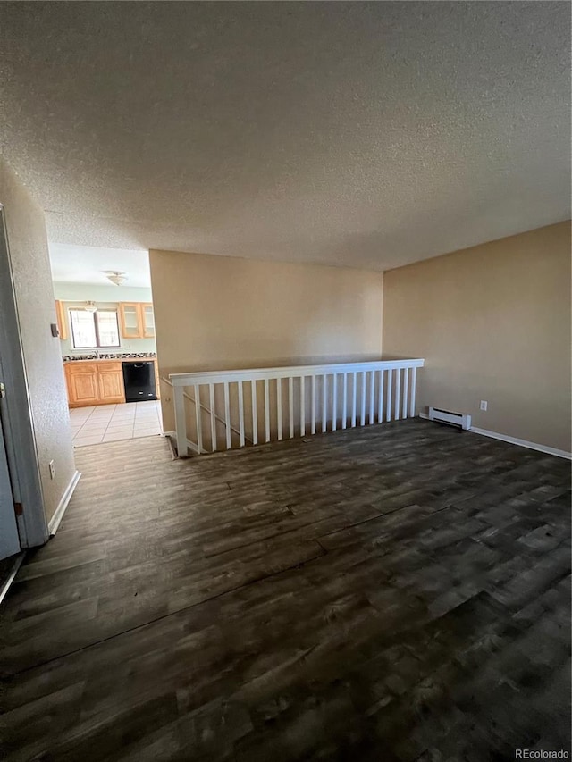 unfurnished room with wood-type flooring, a textured ceiling, and a baseboard radiator