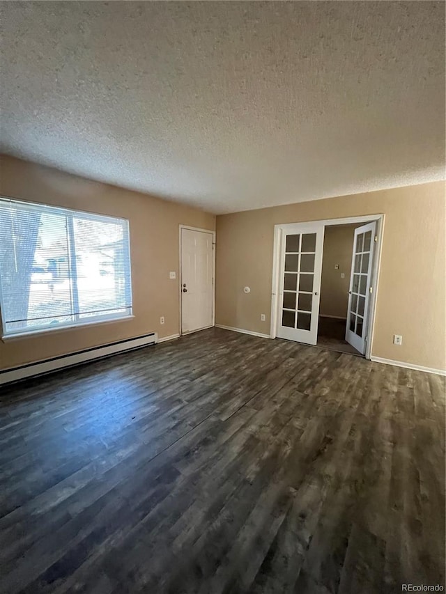 spare room with a textured ceiling, a baseboard heating unit, dark wood-type flooring, and french doors