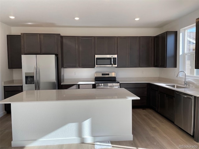 kitchen featuring dark brown cabinetry, sink, a center island, light hardwood / wood-style flooring, and appliances with stainless steel finishes