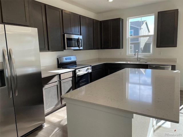 kitchen featuring light stone counters, dark brown cabinets, stainless steel appliances, and a center island