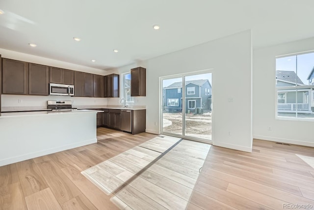 kitchen with a sink, stainless steel appliances, light wood finished floors, and light countertops