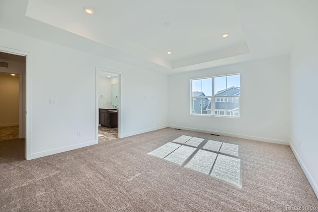 unfurnished bedroom featuring baseboards, visible vents, light colored carpet, a tray ceiling, and recessed lighting