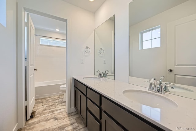 bathroom featuring a sink, toilet, and double vanity