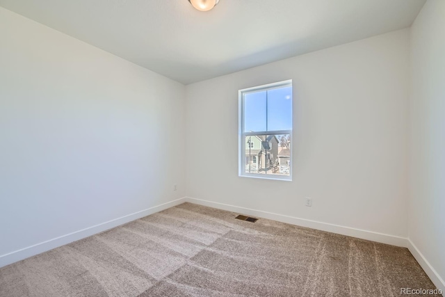 unfurnished room with carpet, visible vents, and baseboards