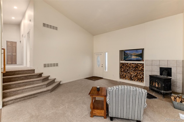 living room featuring carpet, high vaulted ceiling, and a wood stove