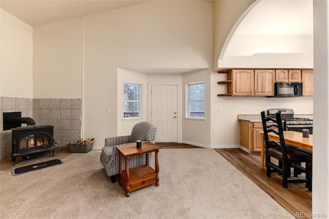 living room featuring vaulted ceiling, a wood stove, and light hardwood / wood-style flooring