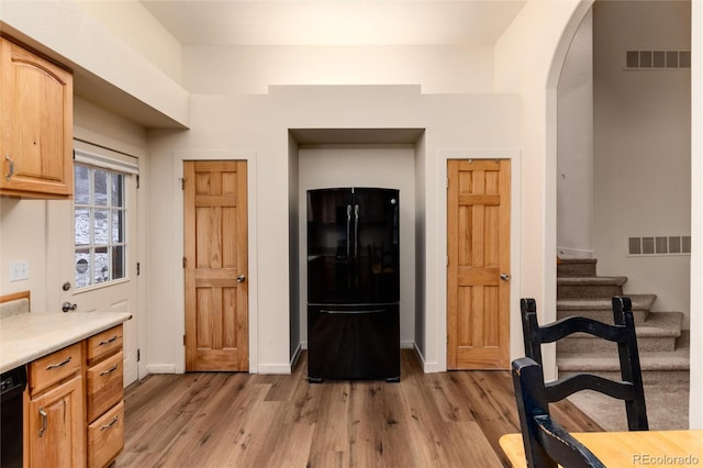 kitchen featuring light brown cabinetry, black appliances, and light hardwood / wood-style flooring