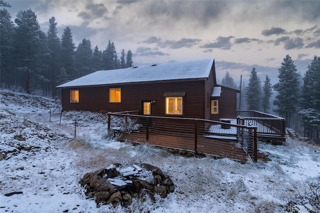 snow covered back of property with a deck