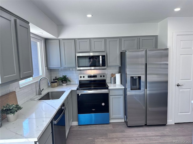 4382 S Xenon St, Morrison, CO 80465 - kitchen with appliances with stainless steel finishes, gray cabinets, light stone counters, backsplash, and wood finished floors