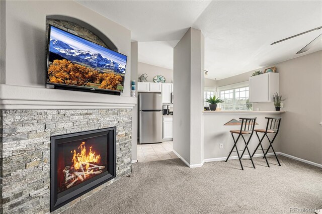 6840 Xavier Cir Unit 5, Westminster, CO 80030 - living area featuring light carpet, a ceiling fan, baseboards, a stone fireplace, and lofted ceiling